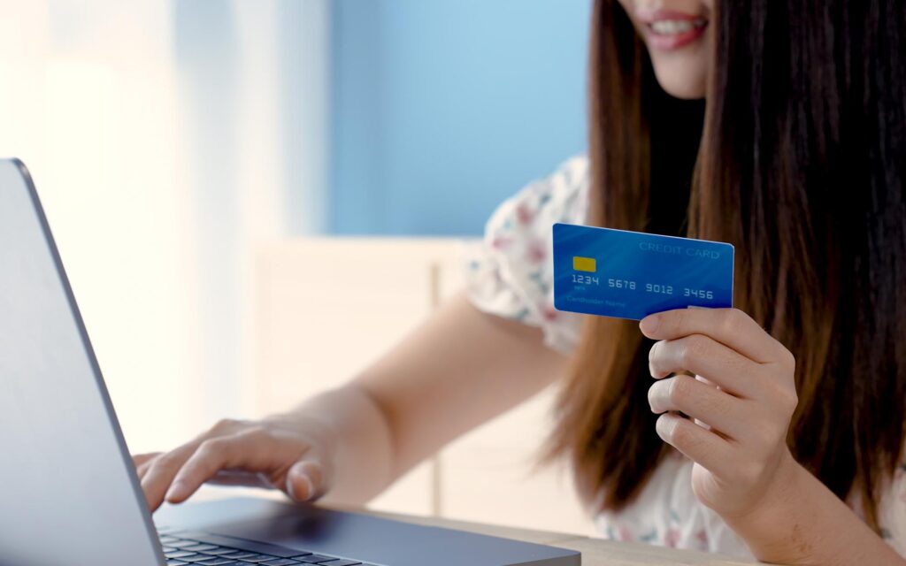 Shopper holding credit card entering payment information into computer.